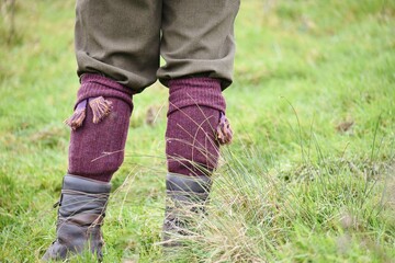 The legs of a a Gamekeeper stood in a field in uniform.