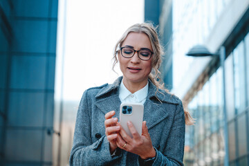 Young woman using smartphone outdoors in a modern urban environment during the day