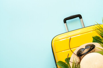 Suitcase, hat and sunglasses on blue background.