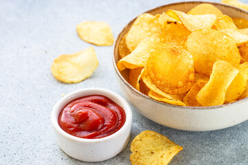 Potato chips in the bowl and ketchup sauce.