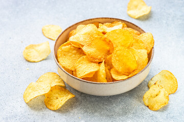 Potato chips in wooden bowl on white table. Top view.