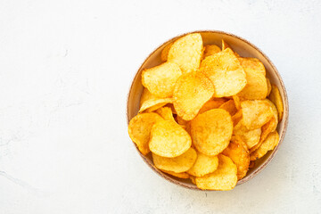 Potato chips in wooden bowl on white table. Top view.