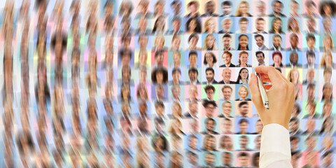 Hand mit Stift sucht in vielen Business Portraits nach richtiger Bewerbung