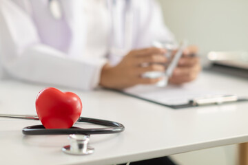 stethoscope for checking heart rhythm and red heart is placed on table in doctor office ready for...