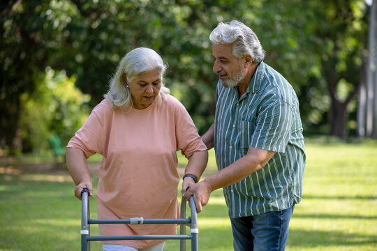 Indian elder woman holding a walker and walking with husband in the park. Concept : Healthy Elder Woman.