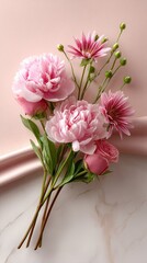 Delicate pink peonies and roses are arranged on a soft pastel pink background, creating an elegant display perfect for any design project