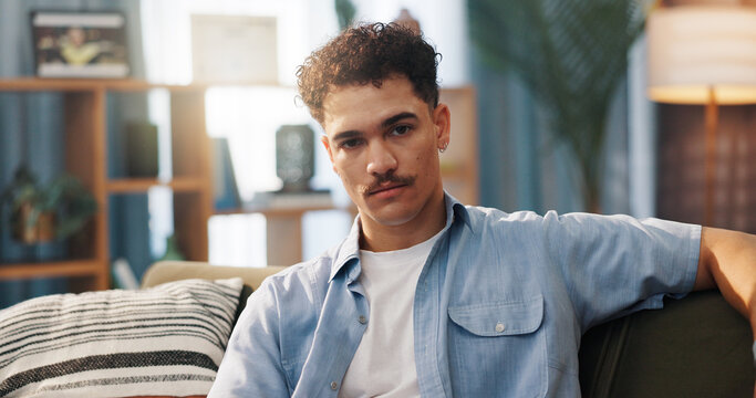 Man, sofa and serious in portrait in home, relax on day off or weekend break with confidence in living room. Calm, rest and comfortable on couch, male person with attitude and chill in house
