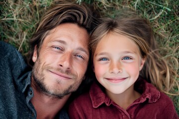 Fototapeta premium Father and Daughter Smiling While Lying on the Grass