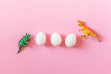 Easter egg hunt holiday composition, white eggs with dinosaur on light pastel pink backgroind. Seasonal spring kids game concept. Flat lay, minimal, trendy, top view, place for text, banner