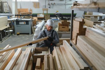 Carpenter inspecting wooden plank in furniture factory