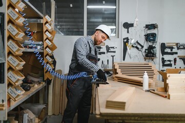Carpenter working wood in furniture factory using pneumatic tool