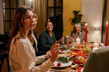 Woman talking while sitting at a table with family and guests