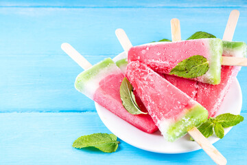 Tasty sweet watermelon ice cream lollies on blue wooden table, top view. Summer vacation and...