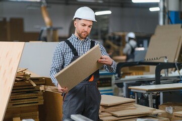 Skilled worker inspecting material in furniture factory