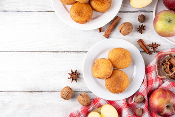 Tasty homemade apple pie autumn tasty donuts with cinnamon sugar glazing and apple jam filling, with fresh apples and spices on white wooden background copy space
