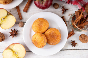 Tasty homemade apple pie autumn tasty donuts with cinnamon sugar glazing and apple jam filling, with fresh apples and spices on white wooden background copy space