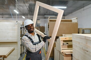 Fototapeta premium Carpenter carrying wooden frame in furniture factory