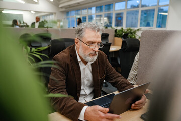 Male worker sitting at a desk and looking at a laptop in front of him