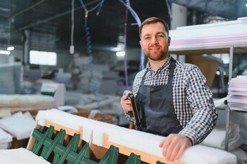 Carpenter working on sofa frame in furniture factory