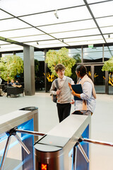 A male intern walks and talks to a female employee walking next to him, near the turnstiles