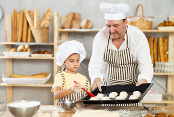 Daughter helps father baker to make pastries, lubricate croissants with loosened egg