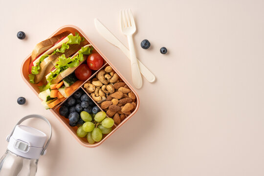 A nutritious lunch box with fruit, sandwich, and nuts, paired with a drink bottle