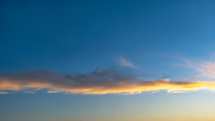 Dramatic sky at dusk. Golden clouds illuminated against a deep blue backdrop create a striking, atmospheric scene