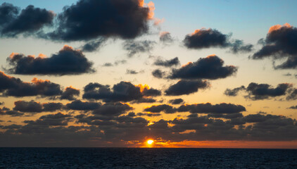 Dramatic sunset over the ocean. Fiery sky peeks through dark clouds creating a stunning, peaceful...