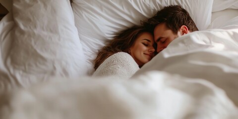 Young loving couple cuddling in bed in the morning. Young man and woman hugging laying on white sheets. Husband and wife in love.
