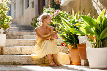 Smiling woman in dress walking in street of Korčula town in Croatia. © nataliaderiabina