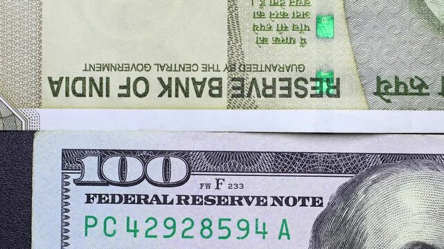 Close up view of rotating American dollar (USD) and Indian rupee (INR) banknotes. Concept of  international commerce, financial partnerships, worldwide trade flows, emerging markets of USA and India.