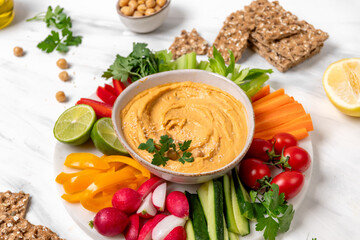 Creamy hummus in a white bowl, garnished with chickpeas and herbs, paired with crispy flatbreads and olive oil, showcasing a vibrant and appetizing snack presentation	