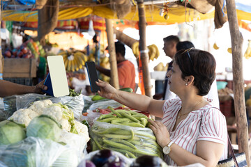 Indian woman having online vegetable payment through phone at store