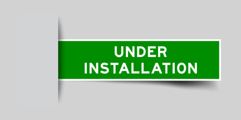 Green color square label sticker with word under installation that inserted in gray background