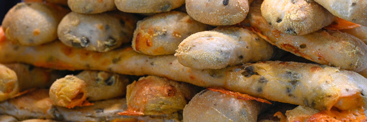 Panorama of freshly baked Cheese and Olive Bread Sticks on a bakery stall at a food market