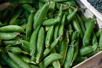 Box of fresh raw pea pods on a greengrocers stall at a food market