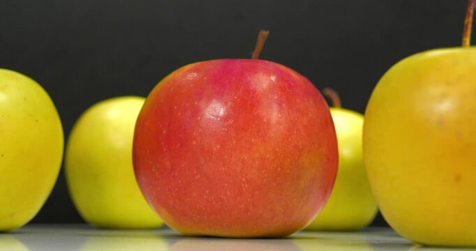 Ripe red and yellow apples rotates on black background, close-up shot