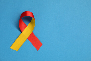 World Hepatitis Day. Yellow-red awareness ribbon on light blue background, top view. Space for text