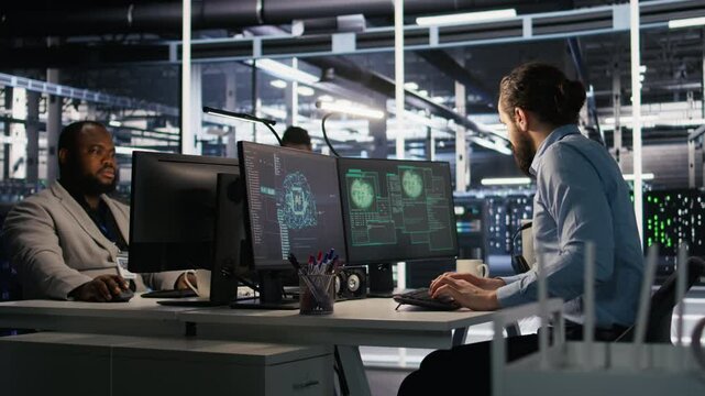 Anxious technicians in data center reacting to system lockdown caused by ransomware alert. IT professionals under pressure evaluating security breaches and scrambling to contain damage, camera A