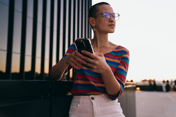 Caucasian woman pauses mid-scroll, holding phone and looking away, reflecting on messages or notifications, capturing the intersection of tech focus and real-world awareness