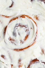 Close up of baked cinnabons with golden crust smeared with cream cheese and cream. Sweet roll buns with cinnamon, yeast pastry. Homemade dessert. Flat lay food. Macro food photography 