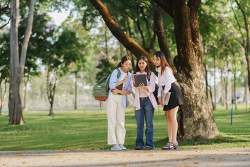 Fototapeta premium Group of university students collaborating on a project outdoors in a sunny park, using a tablet and enjoying their time together