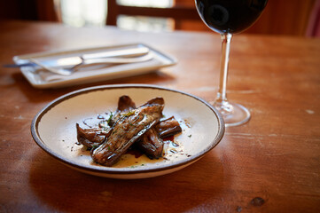 A plate of food with a glass of wine on a table. The plate has a piece of meat and a piece of fish
