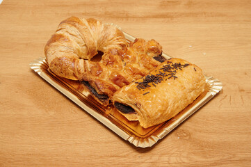A tray of pastries including a croissant, a chocolate roll, and a chocolate roll with sprinkles