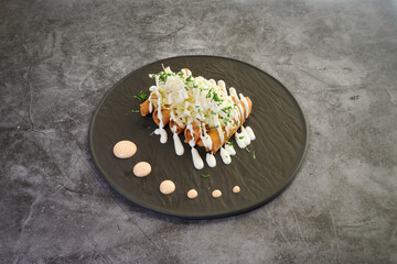 A plate of food with a sauce on it. The sauce is red and white. The plate is black