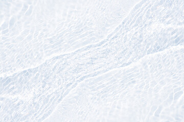 White water with ripples on the surface. Defocus blurred transparent white colored clear calm water surface texture with splashes and bubbles. Water waves with shining pattern texture background.