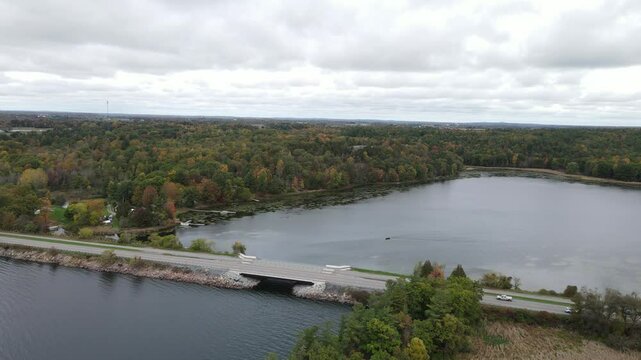Drone view of highway spanning the Lake of Landon Bay Centre surrounded by forests on overcast day