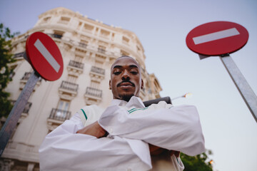Urban fashion meets attitude as young black male poses with determination near no-entry traffic signs.Male modern style, clean lines, and bold stance capture the essence of contemporary street fashion