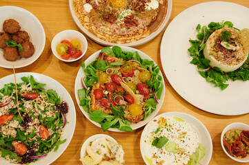 A table with many different types of food, including a salad, a pizza, and a quiche