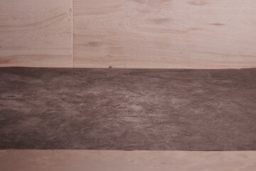 A wooden floor with a grey carpet on top. The floor is made of wood and has a slightly worn appearance